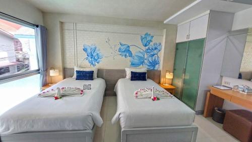 two beds in a room with blue flowers on the wall at Phi Phi Indigo Hotel in Phi Phi Don