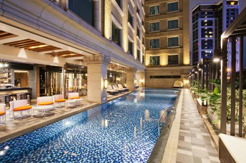Una piscina de hotel con sillas y un bar. en Miramar Garden Taipei, en Taipéi