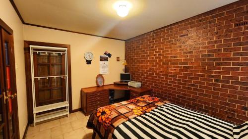 a bedroom with a brick wall and a bed and a desk at Peaceful Haven in Adelaide