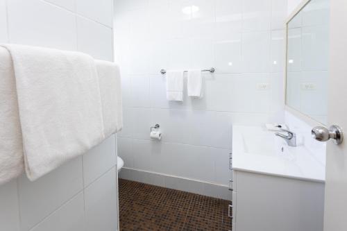 a white bathroom with a sink and a tub at Fig Tree Motel in Narrandera
