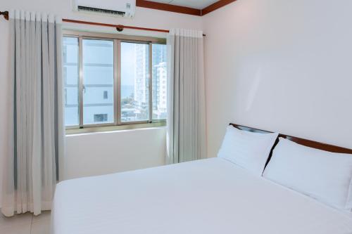 a bedroom with a white bed and a large window at Phúc Đạt Hotel in Vung Tau
