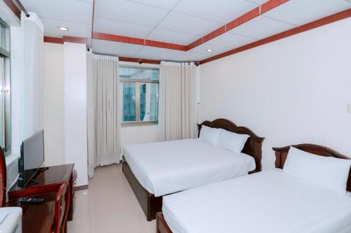 a hotel room with two beds and a television at Phúc Đạt Hotel in Vung Tau