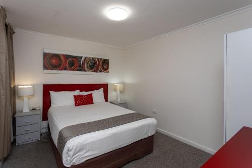 a bedroom with a bed with a red headboard at Fig Tree Motel in Narrandera