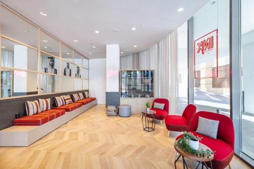 a lobby with red chairs and a couch and a table at Ink Hotel in Dubai