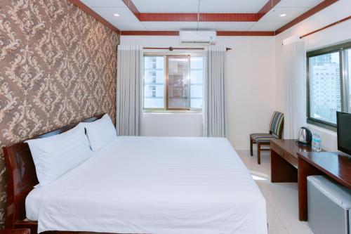 Schlafzimmer mit einem Bett, einem Schreibtisch und einem TV in der Unterkunft Phúc Đạt Hotel in Vũng Tàu