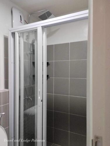 a shower with a glass door in a bathroom at Travel and Lodge Palawan in Puerto Princesa City