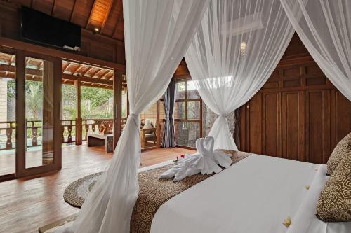a bedroom with a bed with a white canopy at Ithaca Ubud Villa in Ubud