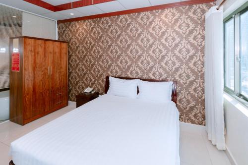 a bedroom with a bed and a wall with a window at Phúc Đạt Hotel in Vung Tau