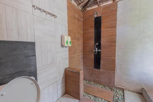 La salle de bains est pourvue d'une douche et d'un mur en bois. dans l'établissement Golden Hill Cottage Nusa Penida, à Nusa Penida