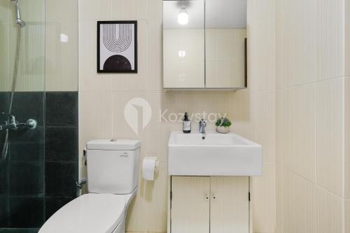 a bathroom with a white toilet and a sink at Sovrae by Kozystay - Grogol in Jakarta