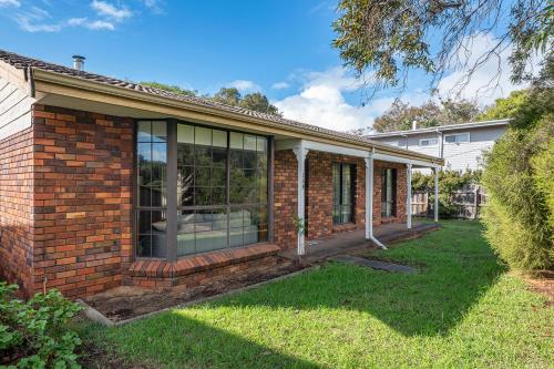a brick house with glass windows and a yard at Seaside Getaway in Dunsborough