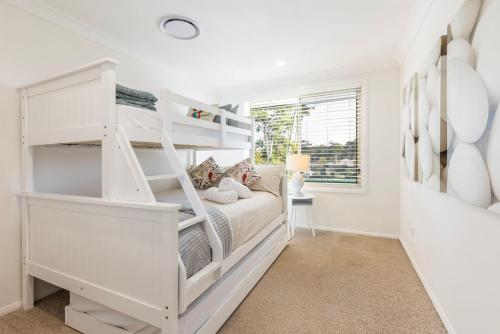 a white bedroom with a bunk bed and a window at Anglesey - Pet Friendly with Pool - 4 Mins Walk to Beach in Callala Bay