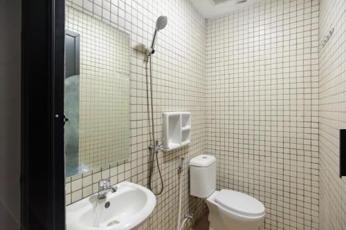 une salle de bain avec toilettes, lavabo et miroir dans l'établissement RedDoorz near Jakarta International Velodrome, à Jakarta