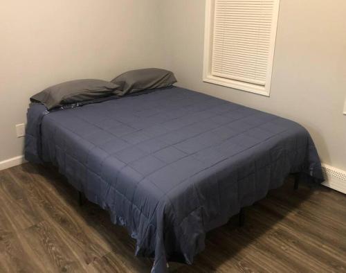 a bed in a room with a blue comforter at Private 2-bedroom with free parking and direct bus to NYC Manhattan only 2 blocks away in Linden