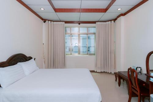 a bedroom with a bed and a desk and a window at Phúc Đạt Hotel in Vung Tau