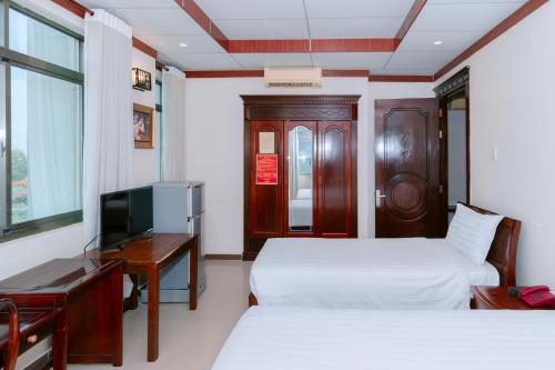 a hotel room with two beds and a desk and a television at Phúc Đạt Hotel in Vung Tau