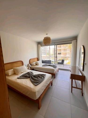 Un dormitorio con dos camas y un balcón. en Marassi North Coast, en El Alamein