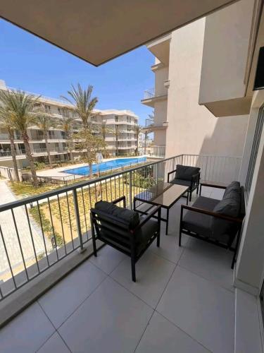 Un balcón con bancos y una piscina. en Marassi North Coast, en El Alamein