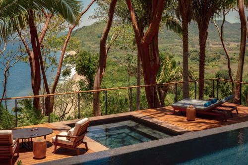 a swimming pool with a table and chairs and trees at One&Only Mandarina in Lo de Marcos