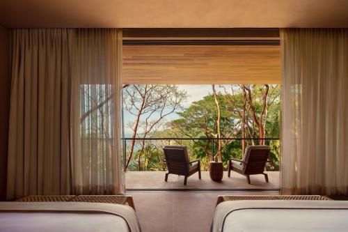 a room with two chairs and a large window at One&Only Mandarina in Lo de Marcos
