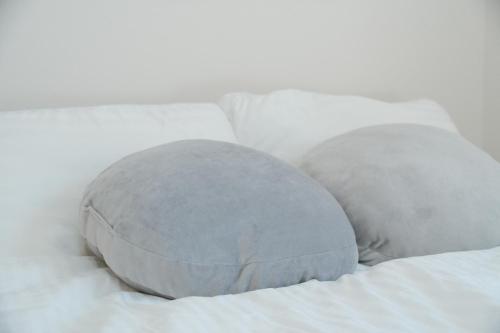 due cuscini appoggiati sopra un letto bianco di CON-TWO 201 a Tokyo