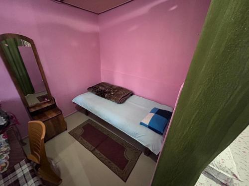 a small pink room with a bed and a mirror at Orchid Park Homestay in Sivasagar