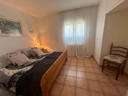 a bedroom with a bed and a chair and a window at Casas Rurales La Picotilla y la Guija in Martiherrero
