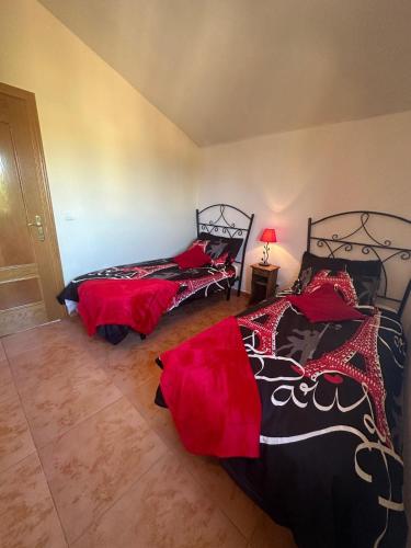 two beds in a room with red and black at Casas Rurales La Picotilla y la Guija in Martiherrero