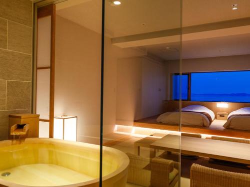 een badkamer met een bad en een slaapkamer met een bed bij Awaji International Hotel The Sunplaza in Sumoto