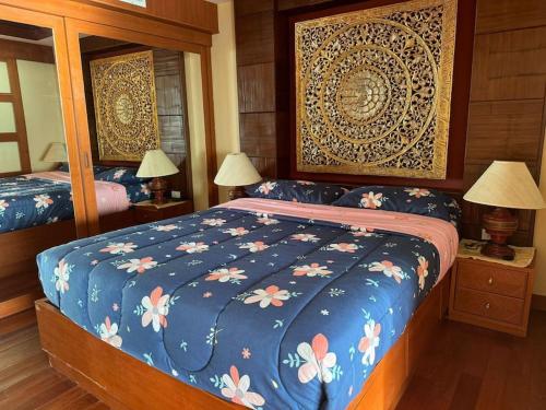 a bedroom with a bed with a blue comforter with flowers at Patong Tower apartment with a great view in Patong Beach