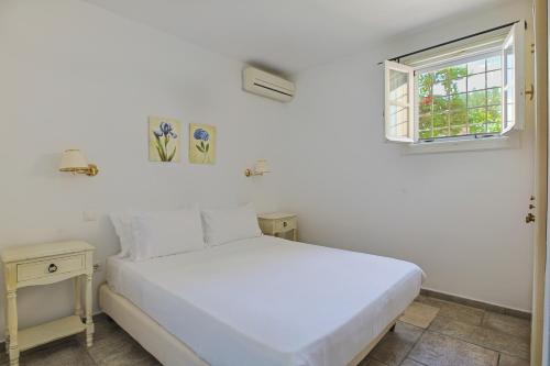 a bedroom with a white bed and a window at Villa Nika in Spetses
