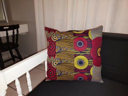 a colorful pillow sitting on a black couch at Fairway Guest Lodge in Margate