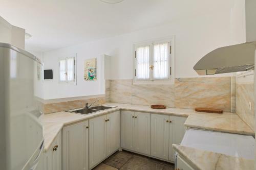 una cocina con armarios blancos y fregadero en Villa Nika, en Spetses