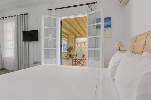 a bedroom with a white bed and a sliding glass door at Villa Nika in Spetses