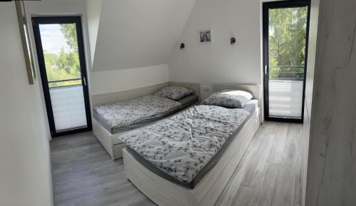 two beds in a room with two windows at Villa LUX Luis in Dziwnów