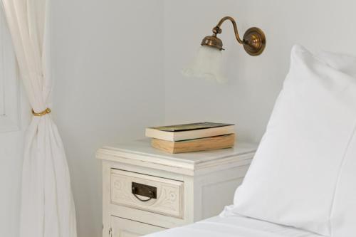 a bedside table with a book and a lamp on it at Villa Nika in Spetses