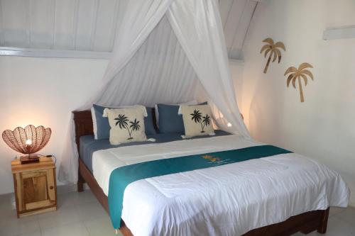 een slaapkamer met een hemelbed bij New Balengkudua Hotel in Gili Air