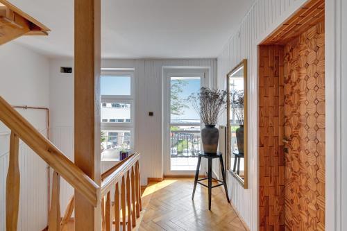 a hallway with a staircase and a vase on a stool at Nadmorski Apartament Z Tarasem Nad Bulwarem in Gdynia