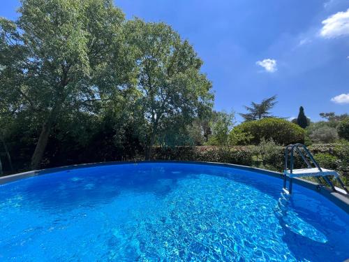 une grande piscine bleue dans une cour arborée dans l'établissement villa avec piscine et grand jardin, à Nîmes