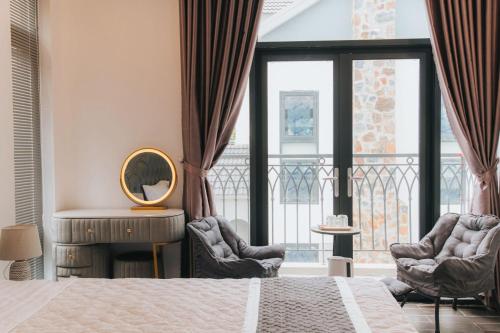a bedroom with a bed and two chairs and a mirror at Khách sạn Hera Hotel in Hà Ðông