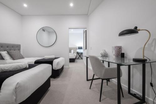 a bedroom with two beds and a desk and a mirror at CBD Apartments by the International in Wagga Wagga