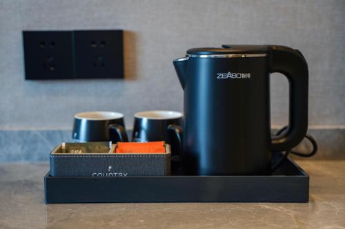 a black coffee pot on a tray with three cups at Country Inn & Suite by Radisson, Guangzhou Huadu Shiling in Huadu