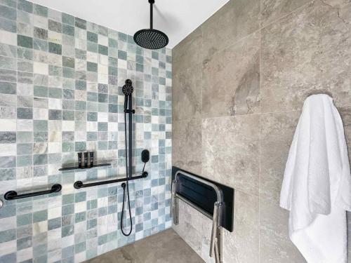 a bathroom with a shower with blue and gray tiles at Petra at Cael's Gate in Broke