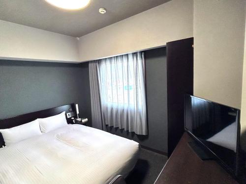 a bedroom with a bed and a flat screen tv at Hotel Route-Inn Morioka Minami Inter in Morioka