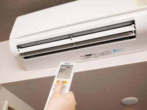 a person holding a remote control in front of a air conditioner at Hotel Route-Inn Morioka Minami Inter in Morioka