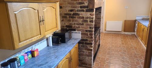 a kitchen with wooden cabinets and a brick wall at Comfort Near Riverside Stadium in Middlesbrough