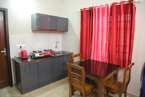 a small kitchen with a table and a red curtain at NR HEAVENZ Near Rajagiri Hospital in Alwaye