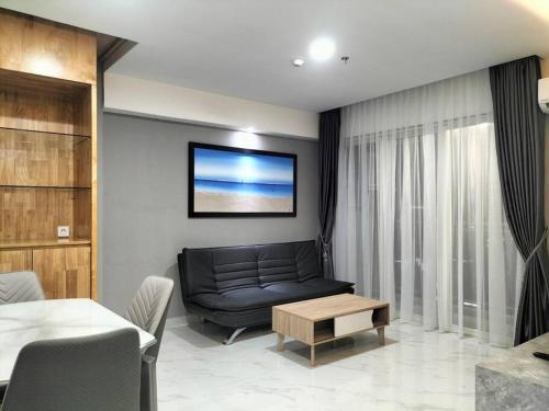 a living room with a black couch and a table at nice apartment with city view at Grand Jati Junction in Medan