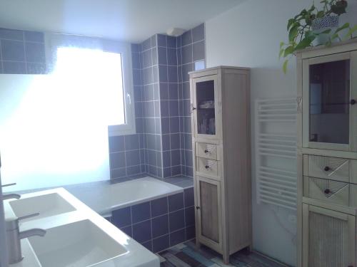 La salle de bains est pourvue d'une baignoire, d'un lavabo et d'une armoire. dans l'établissement Maison bois mer campagne, à Saint-Jean-Trolimon