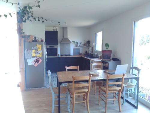 une cuisine avec une table, des chaises et un réfrigérateur dans l'établissement Maison bois mer campagne, à Saint-Jean-Trolimon